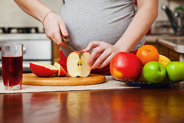 pregnant woman cutting apples