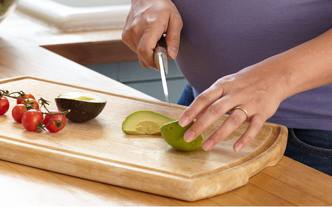 pregnant woman cutting avocado