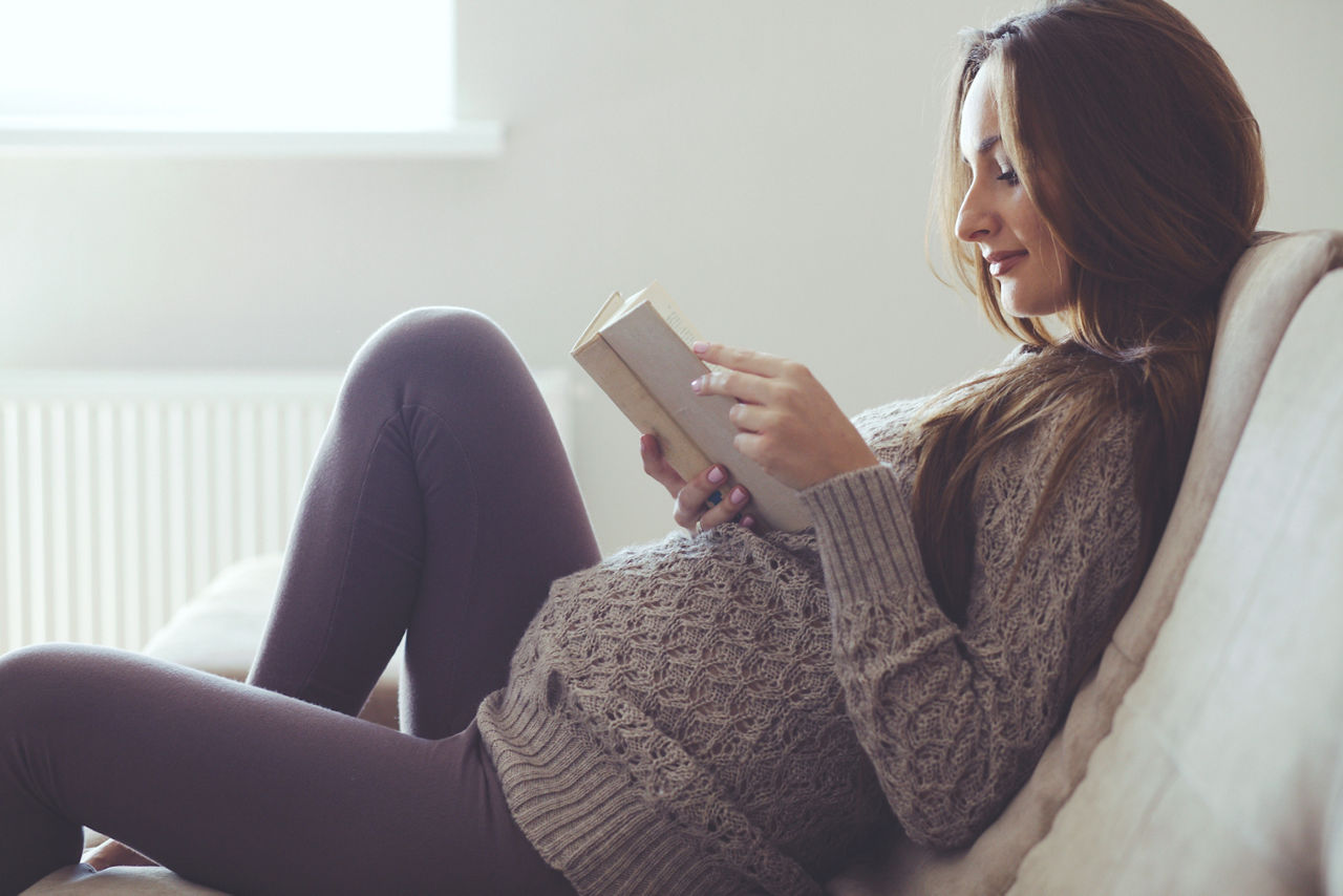 Home cozy portrait of pregnant woman resting at home and reading book on sofa; Shutterstock ID 222996742,pregnant woman relaxing and reading book