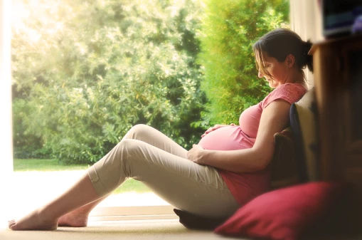 Pregnant woman sitting holding bump