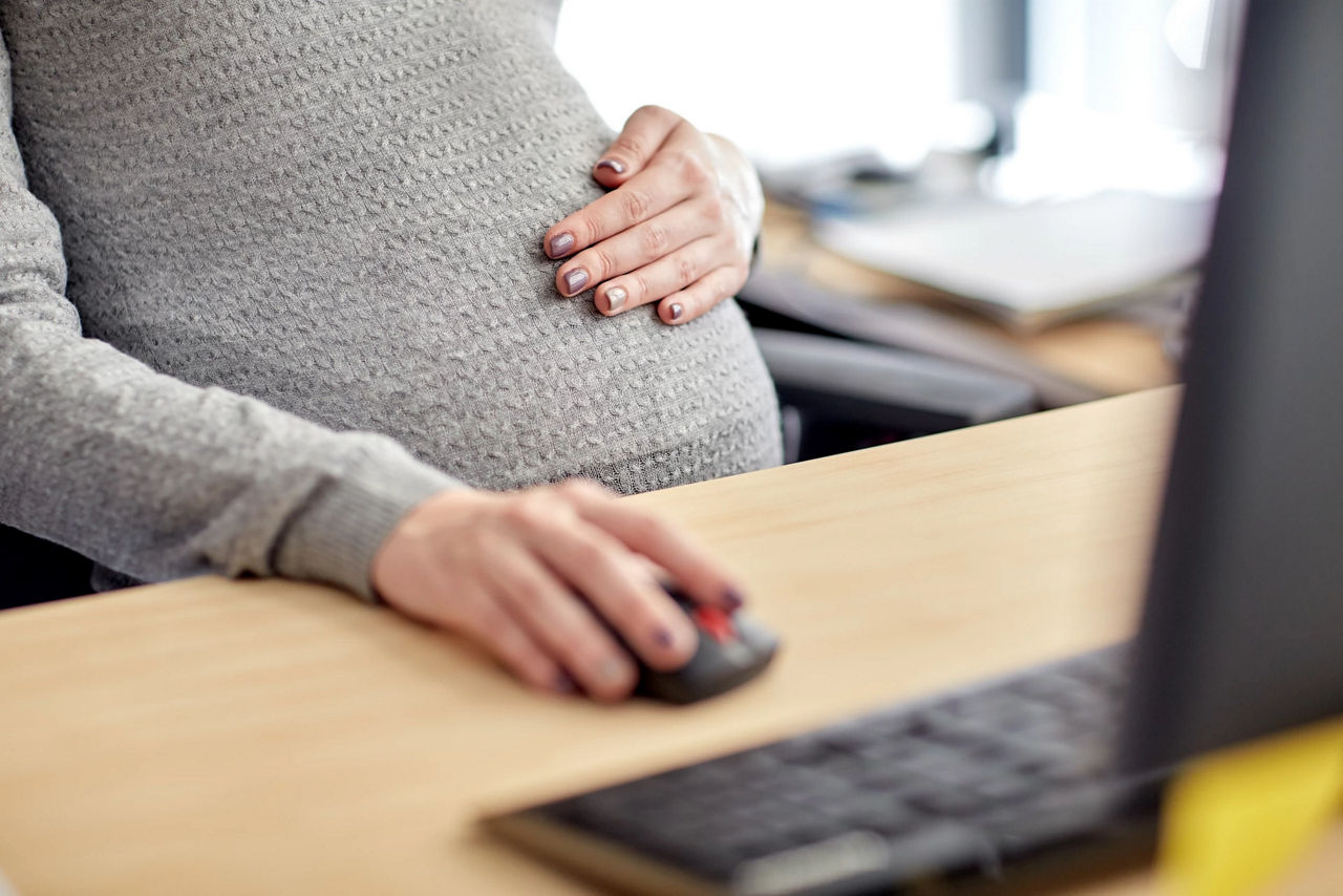 Pregnant businesswoman with computer at office