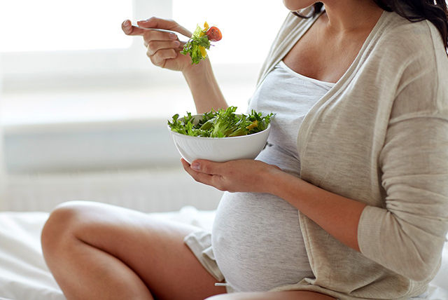 mujer embarazada comiendo saludable ensalada verde