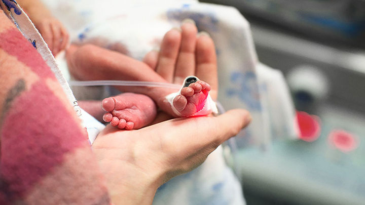 preterm baby held smaller