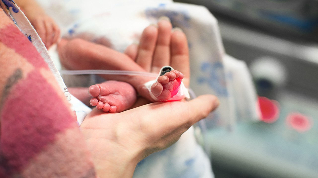 Close-up of a mother holding a pre-term baby's feet in her hand