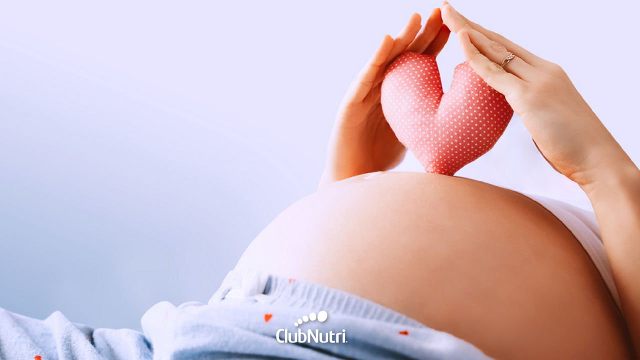 Futura mamá sosteniendo un corazón de peluche sobre su vientre