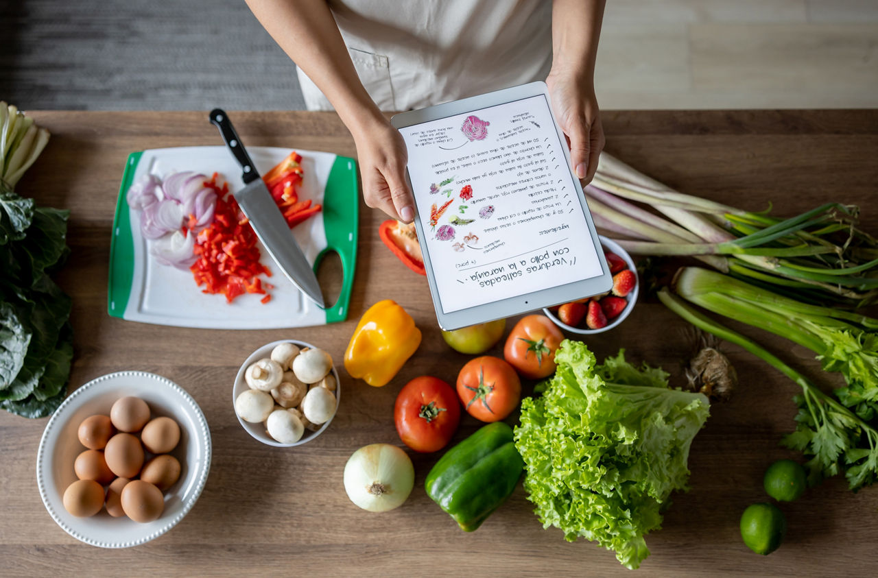 Close-up on a woman cooking at home following an online recipe on a tablet computer