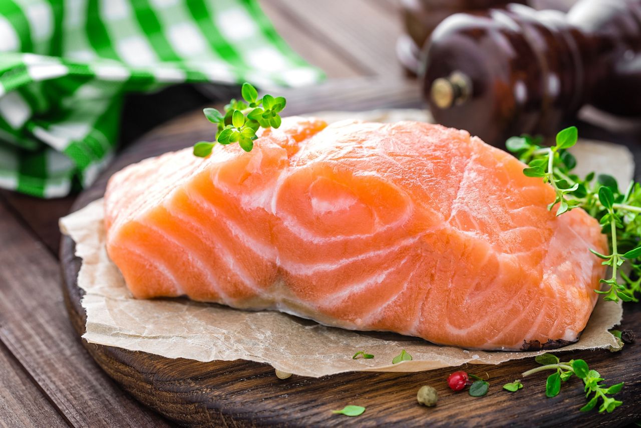 Raw salmon fish fillet on wooden board closeup