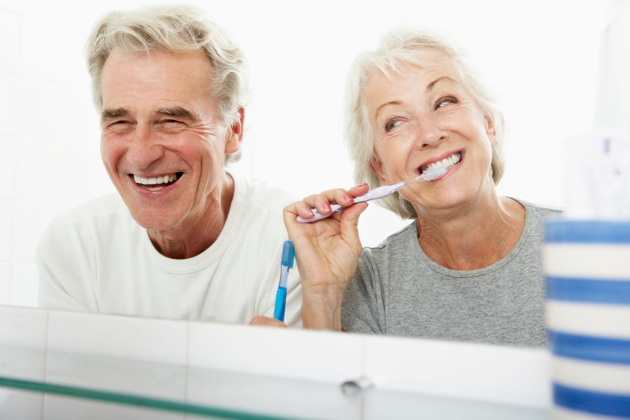 Senior Couple In Bathroom Brushing Teeth Laughing