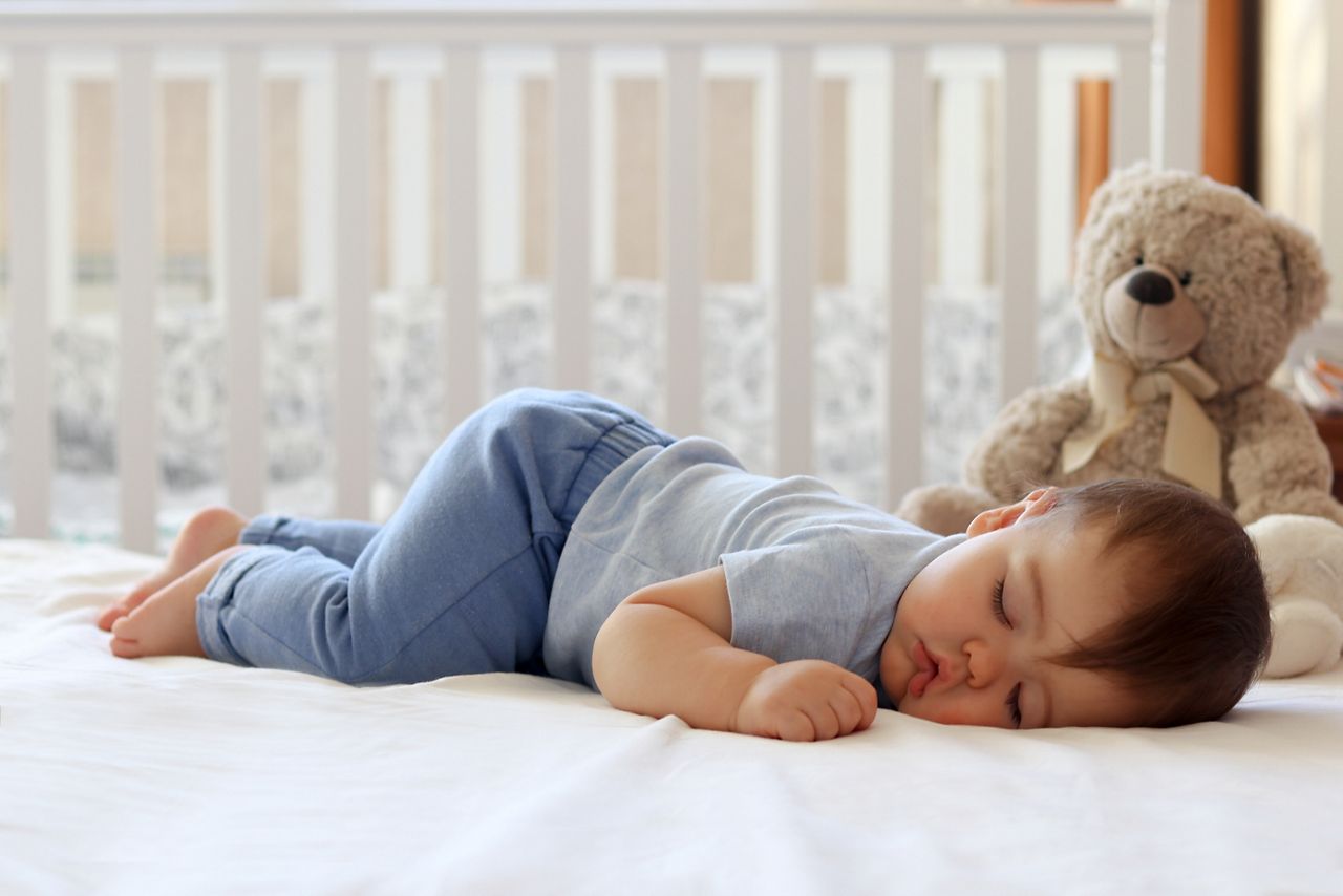 Funny baby sleeping on his stomach on bed at home. Child daytime bottom up sleeping position; Shutterstock ID 1011083761; purchase_order: DNC Thumbnails; job: Webinars 4 ; client: ; other: 