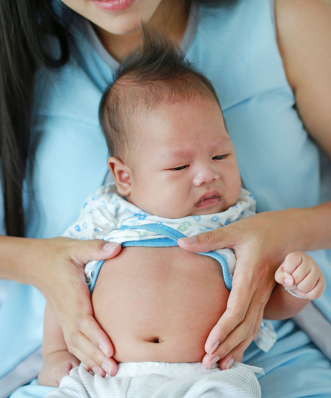 Close-up hands of mother touching and take care infant with pain in her Stomach.; Shutterstock ID 1043392336; purchase_order: -; job: -; client: -; other: -
