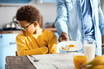 Fussy eater. Pouting pre-teen boy sitting at the table and turning away while refusing to eat a fried egg; Shutterstock ID 1097025746; purchase_order: DNC Thumbnails; job: Webinars 1 (50/189); client: ; other: 