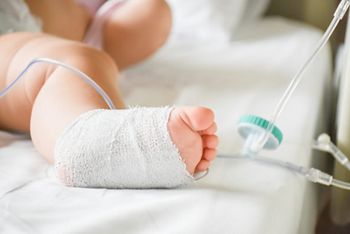 Little sick baby on a drip receiving a saline solution intravenously in the hospital or clinic. Baby with cannula in the feet on a hospital bed; Shutterstock ID 1119664271; purchase_order: DNC Thumbnails; job: Webinars 3 (50/188); client: ; other: 