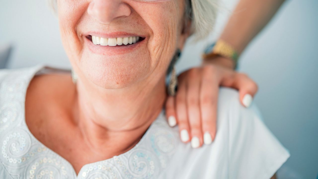Young elegant woman's hand on senior lady's shoulder. Portrait of a smiling old lady with her nurse's hands on her shoulders. Sign of caring for seniors. Helping hands. Care for the elderly concept. ; Shutterstock ID 1166372281; purchase_order: DNC Thumbnails; job: Publications; client: ; other: 