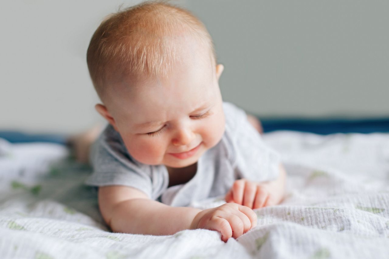Portrait of crying screaming white Caucasian baby girl boy four months old lying on bed in bedroom on tummy. Natural emotion expression. Childhood lifestyle; Shutterstock ID 1369039703; purchase_order: DNC Thumbnails; job: Webinars 2 (50/188); client: ; other: 