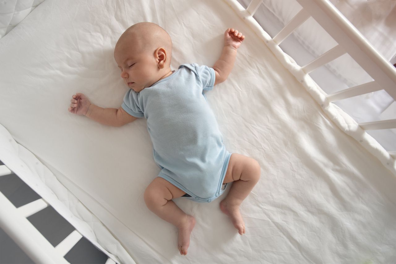 Top view wide angle sleeping newborn baby lies in a crib arms and legs outstretched, baby sleep; Shutterstock ID 1492878422; purchase_order: DNC Thumbnails; job: Documents; client: ; other: 