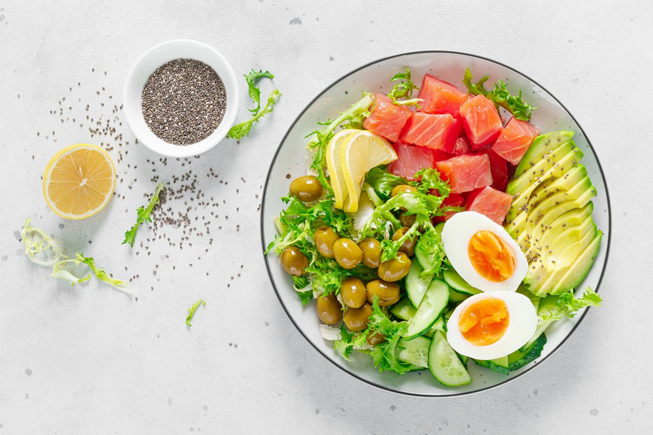 Ketogenic, keto or paleo diet lunch bowl with salted salmon fish, lemon, avocado, olives, boiled egg, cucumber, green lettuce salad and chia seeds. Healthy food trend. Top view; Shutterstock ID 1654712008; purchase_order: DNC Thumbnails; job: Webinars 2 (50/188); client: ; other: 