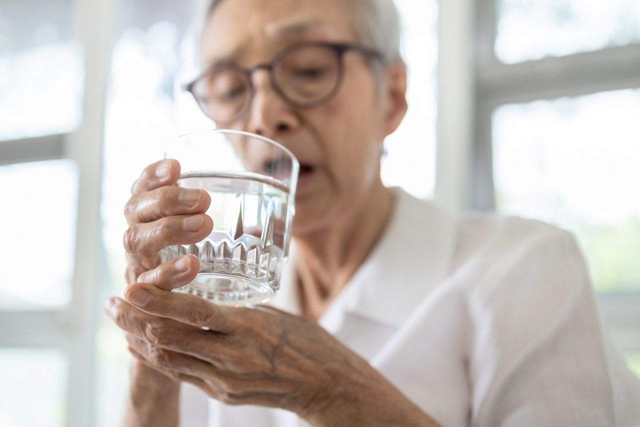 Senior woman holding glass of water,hand shaking while drinking water,elderly patient with hands tremor uncontrolled body tremors,symptom of essential tremor,parkinson's disease,neurological disorders; Shutterstock ID 1685125852; purchase_order: DNC Thumbnails; job: Webinars 2 (50/188); client: ; other: 