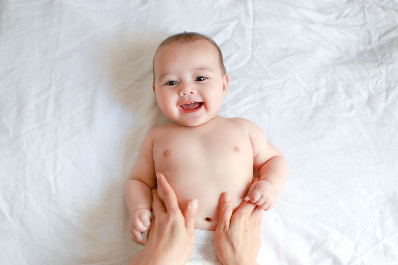 Adorable newborn baby boy with smiling face top view relaxing time doing belly massage by his mother. Mixed race Asian-German infant massaging and laughing.; Shutterstock ID 1773011480; purchase_order: DNC thumbnails; job: N&G videos; client: ; other: 