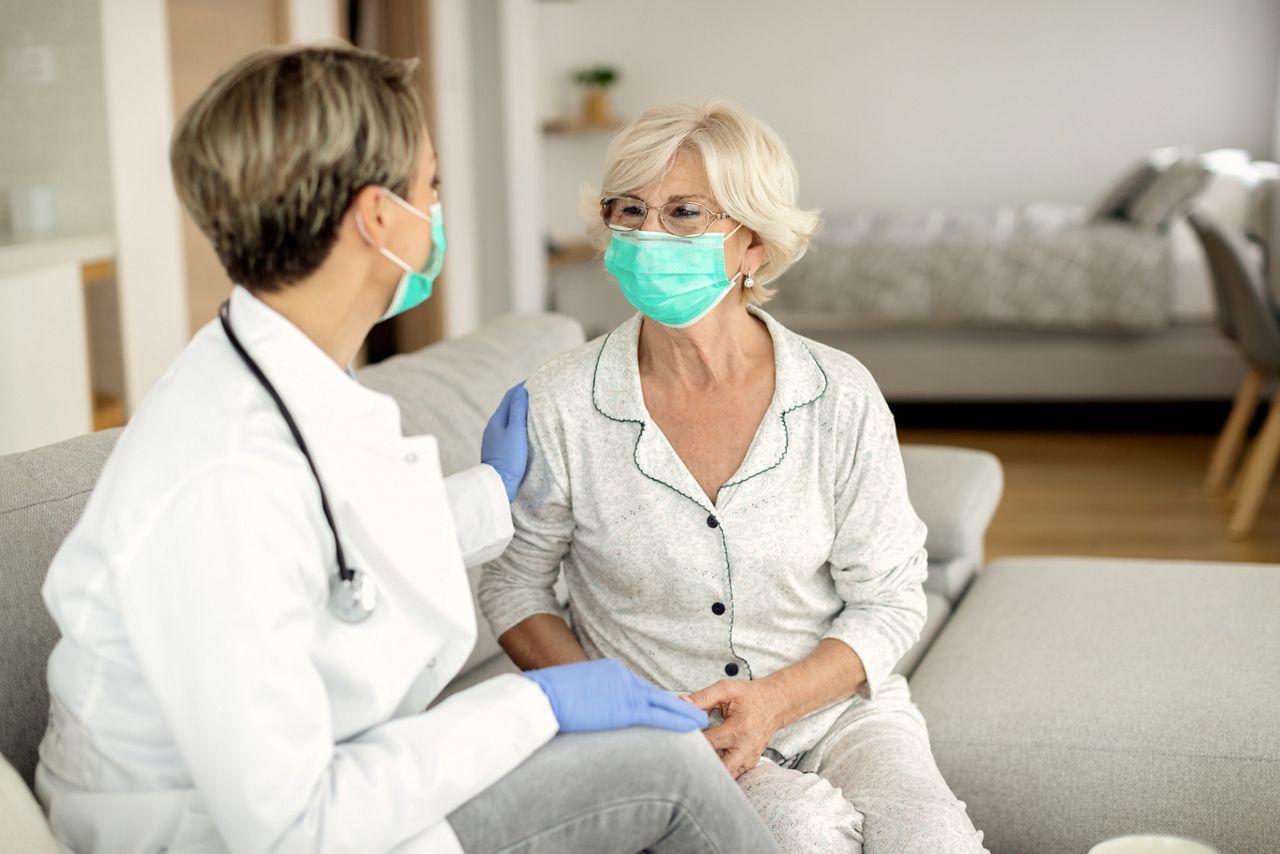 Happy mature woman and female doctor wearing protective face masks during a home visit. ; Shutterstock ID 1786404935; purchase_order: DNC Thumbnails; job: Webinars 3 (50/188); client: ; other: 
