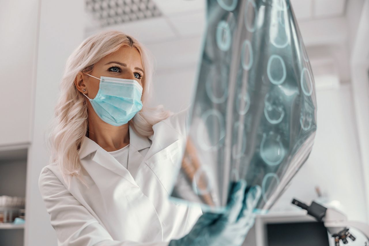 Dedicated doctor holding x-ray of the patient's brain and looking at it.; Shutterstock ID 1805687128; purchase_order: DNC Thumbnails; job: Webinars 2 (50/188); client: ; other: 