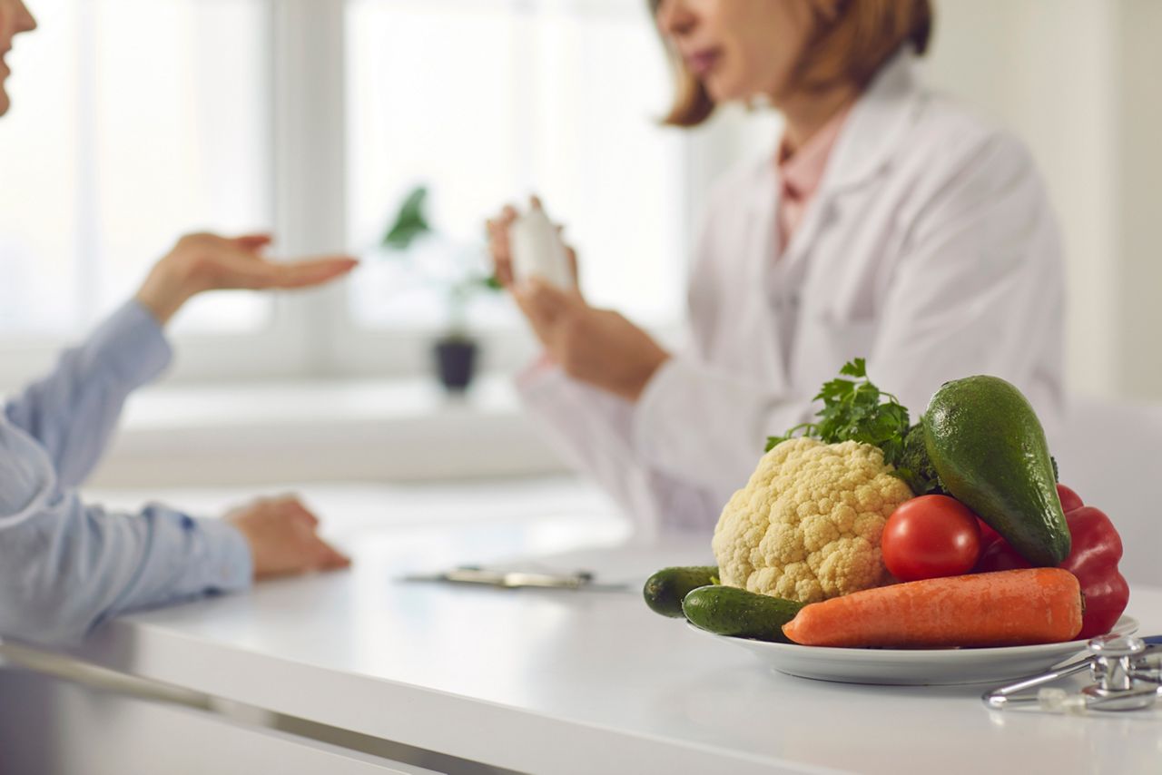 Doctor talking to patient and teaching her to take medicine, eat healthy food and stick to diet. Nutrition education and disease prevention concept. Blurred background, bowl of vegetables in close-up; Shutterstock ID 1896432370; purchase_order: 25 thumbnail photos ; job: ; client: ; other: 
