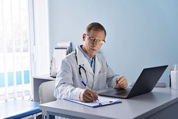 Serious old mature professional male doctor using laptop computer in hospital office watching medical webinar training, writing in healthcare report, consulting patient online at telemedicine meeting.; Shutterstock ID 1902433510; purchase_order: DNC Thumbnails; job: Courses; client: ; other: 