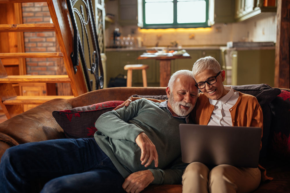 Senior couple using a laptop while relaxing in their lounge
