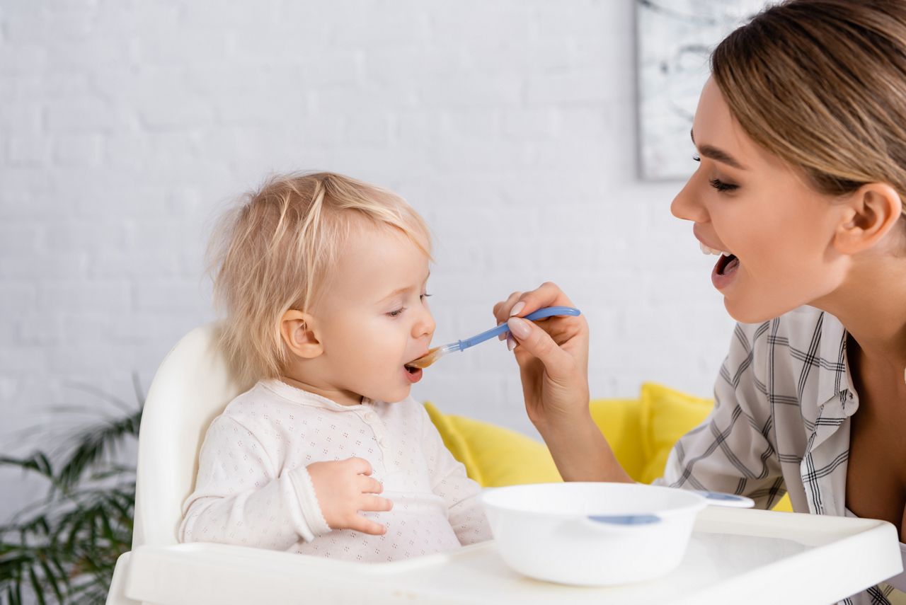 young woman with open mouth feeding toddler son at home; Shutterstock ID 1920114860; purchase_order: DNC Thumbnails; job: Webinars 4 ; client: ; other: 