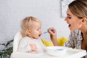 young woman with open mouth feeding toddler son at home; Shutterstock ID 1920114860; purchase_order: DNC Thumbnails; job: Webinars 4 ; client: ; other: 