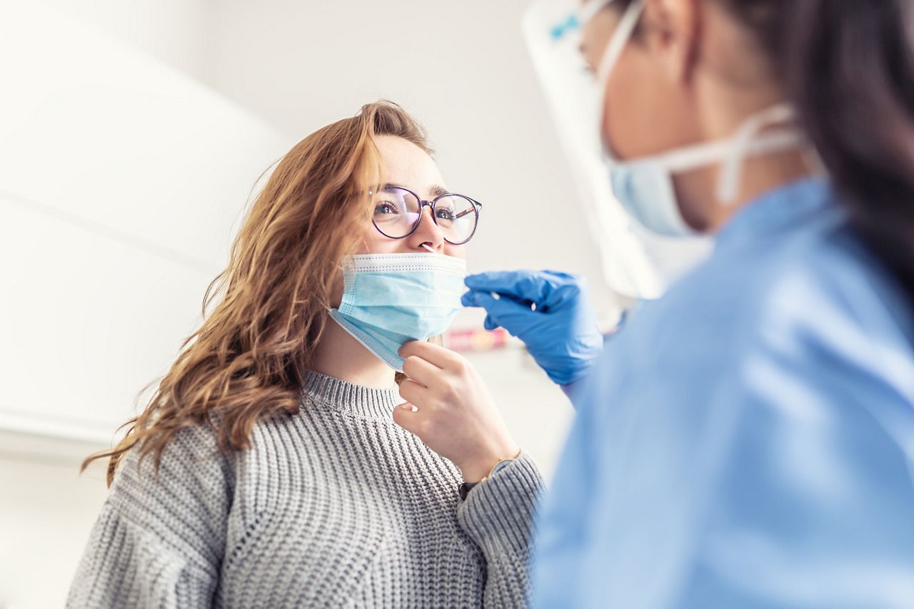 Smiling girl puts face mask off her nose so that a healthcare worker can take a sample for Covid-19 testing.; Shutterstock ID 1934424008; purchase_order: DNC Thumbnails; job: Infographics; client: ; other: 