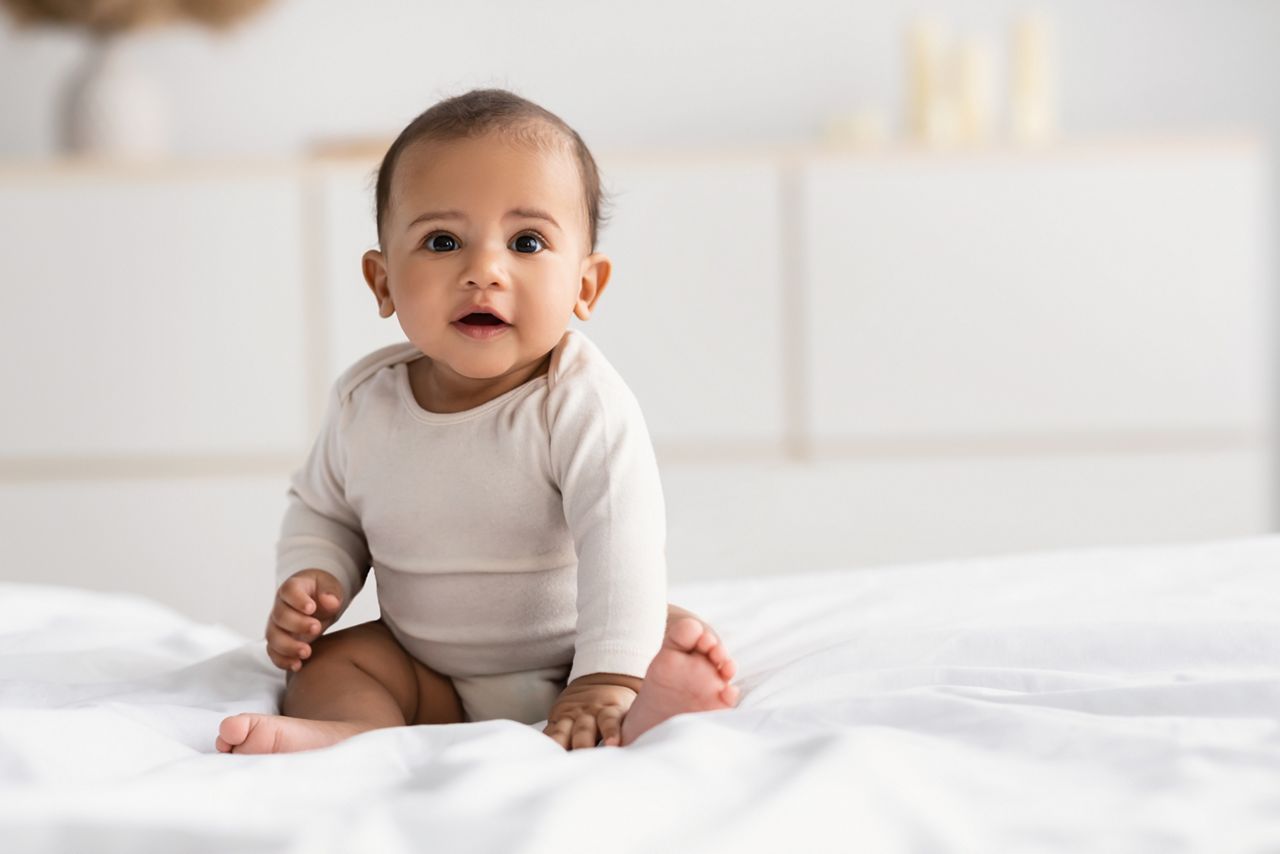Cute little African American infant sitting on bed; Shutterstock ID 1937038210; purchase_order: DNC Thumbnails; job: Webinars 3 (50/188); client: ; other: 
