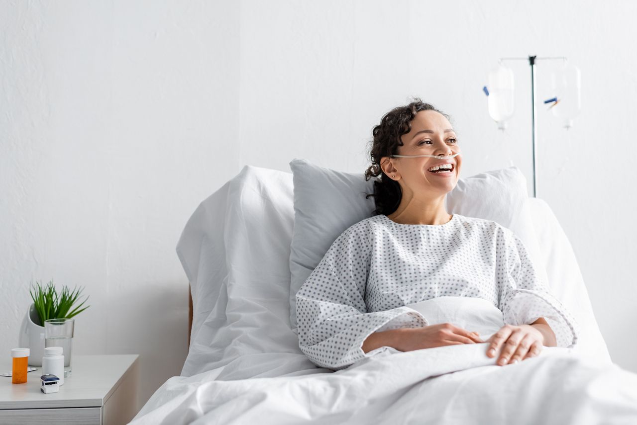 happy african american woman laughing while sitting in hospital bed; Shutterstock ID 1960549015; purchase_order: DNC Thumbnails; job: Articles; client: ; other: 