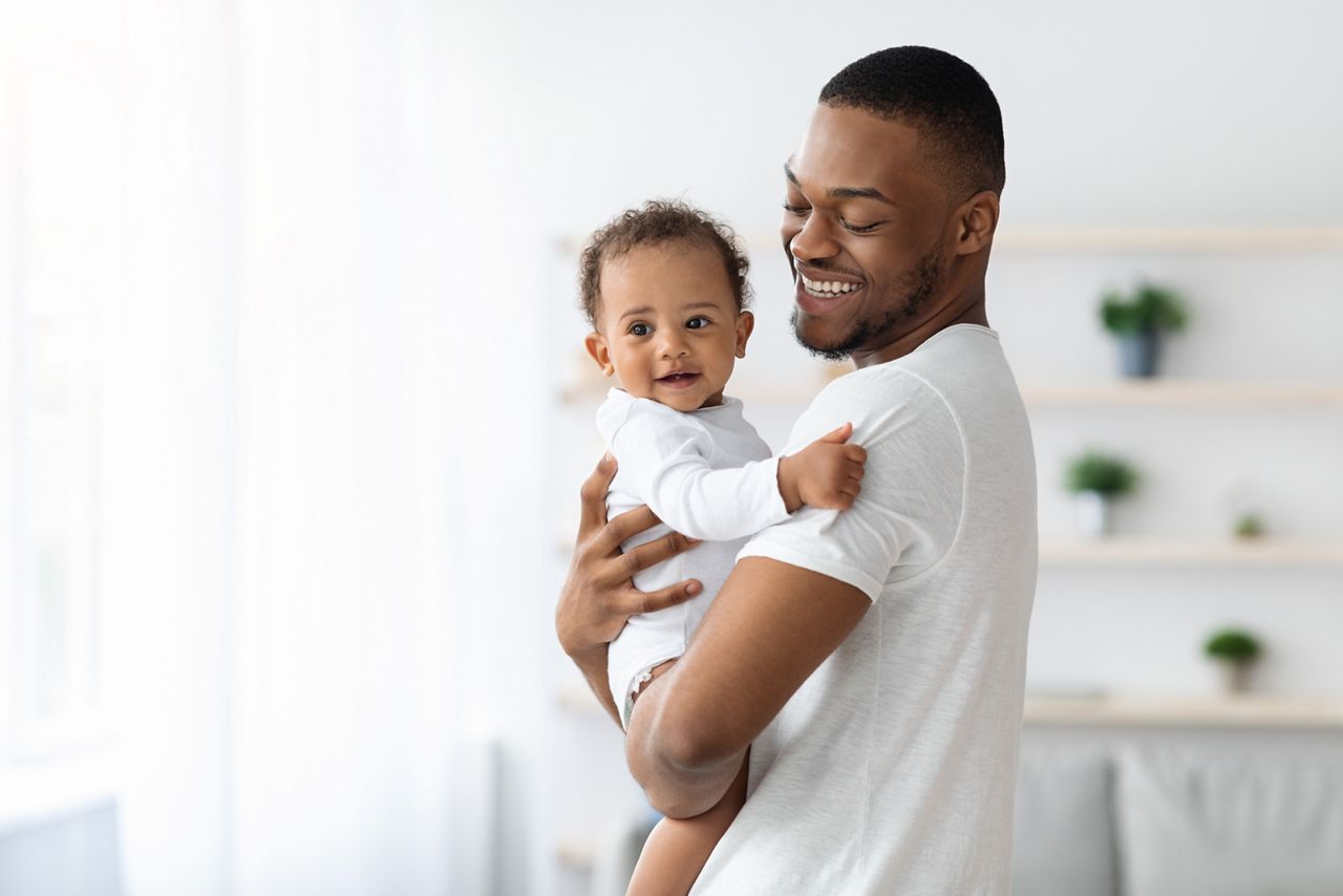 Happiness Of Fatherhood. Portrait of young black dad with cute little baby on his hands standing near window at home, loving african american father spending time with infant child, copy space; Shutterstock ID 2018765327; purchase_order: DNC Thumbnails; job: Webinars 3 (50/188); client: ; other: 