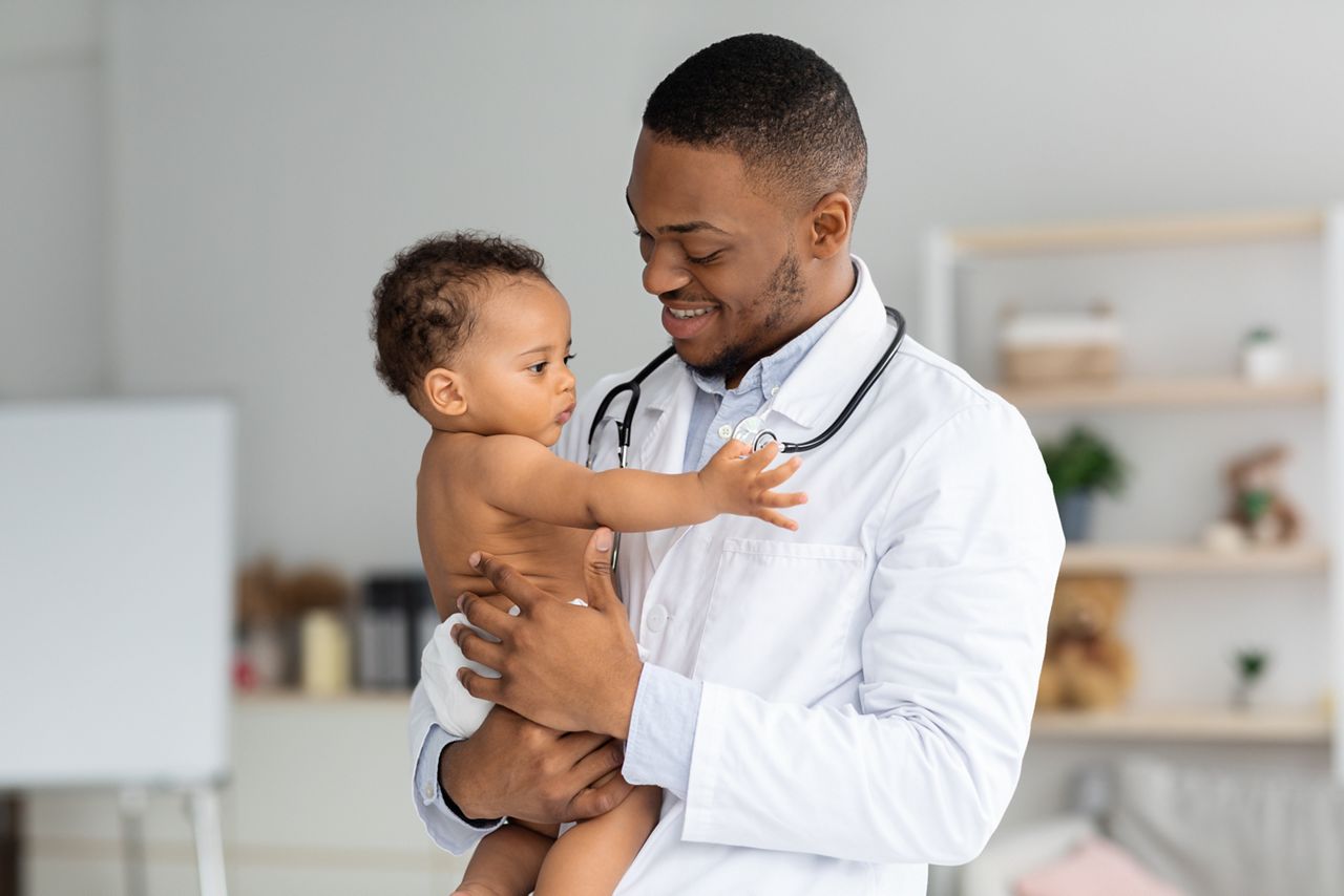 Portrait Of Handsome Young Black Pediatrician Holding Adorable Little Infant Boy In Hands, Cute Toddler Child Playing With Stethoscope On Doctor's Neck While Having Medical Check Up In Clinic; Shutterstock ID 2018780882; purchase_order: DNC Thumbnails; job: Webinars 1 (50/189); client: ; other: 