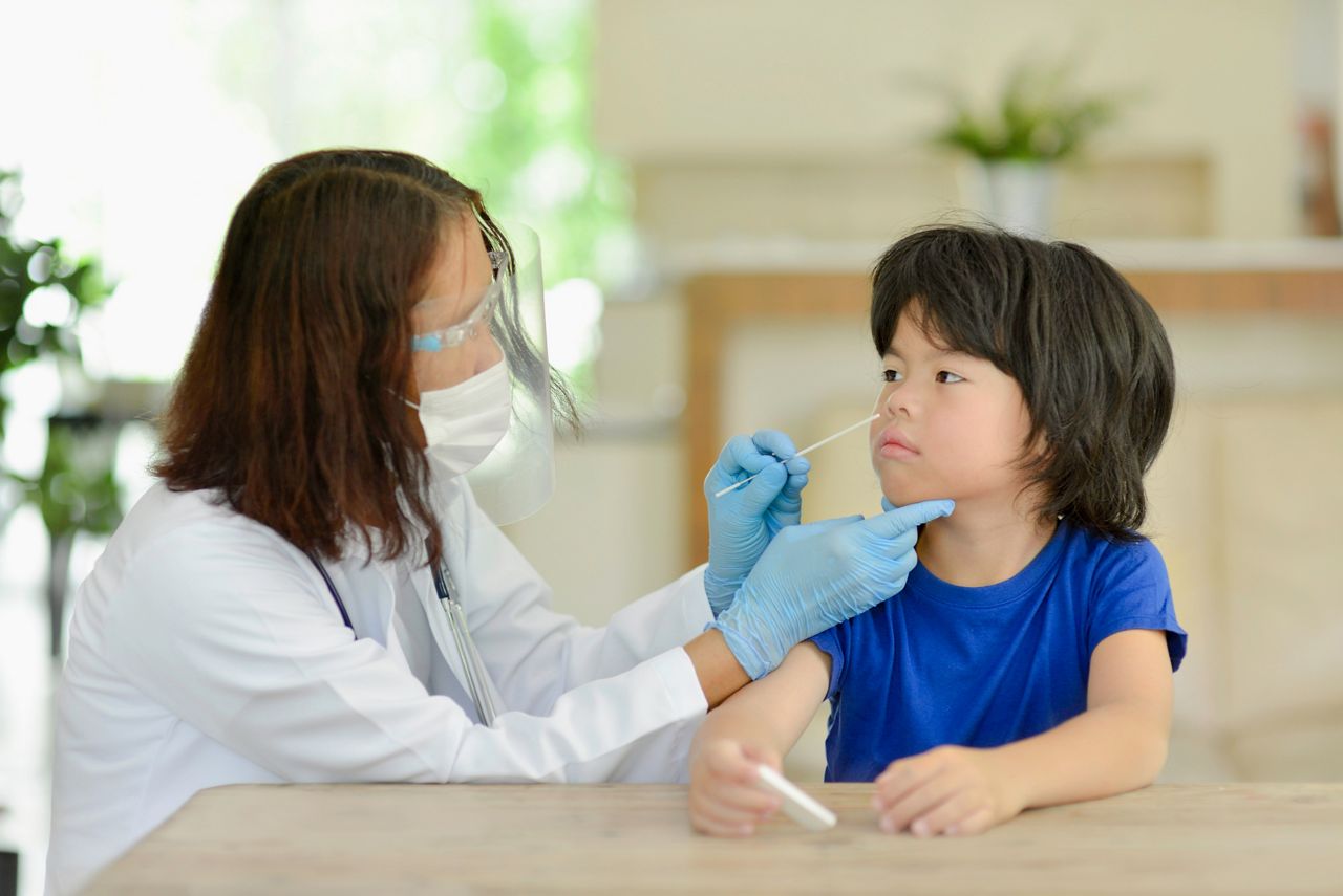 Female pediatrician using a swab to take a sample from a patient's nose.Medical worker taking mucus specimen from potentially infected Asian child. Covid-19 nasal swab test.; Shutterstock ID 2027876456; purchase_order: DNC Thumbnails; job: Articles ; client: ; other: Replace Fishwife