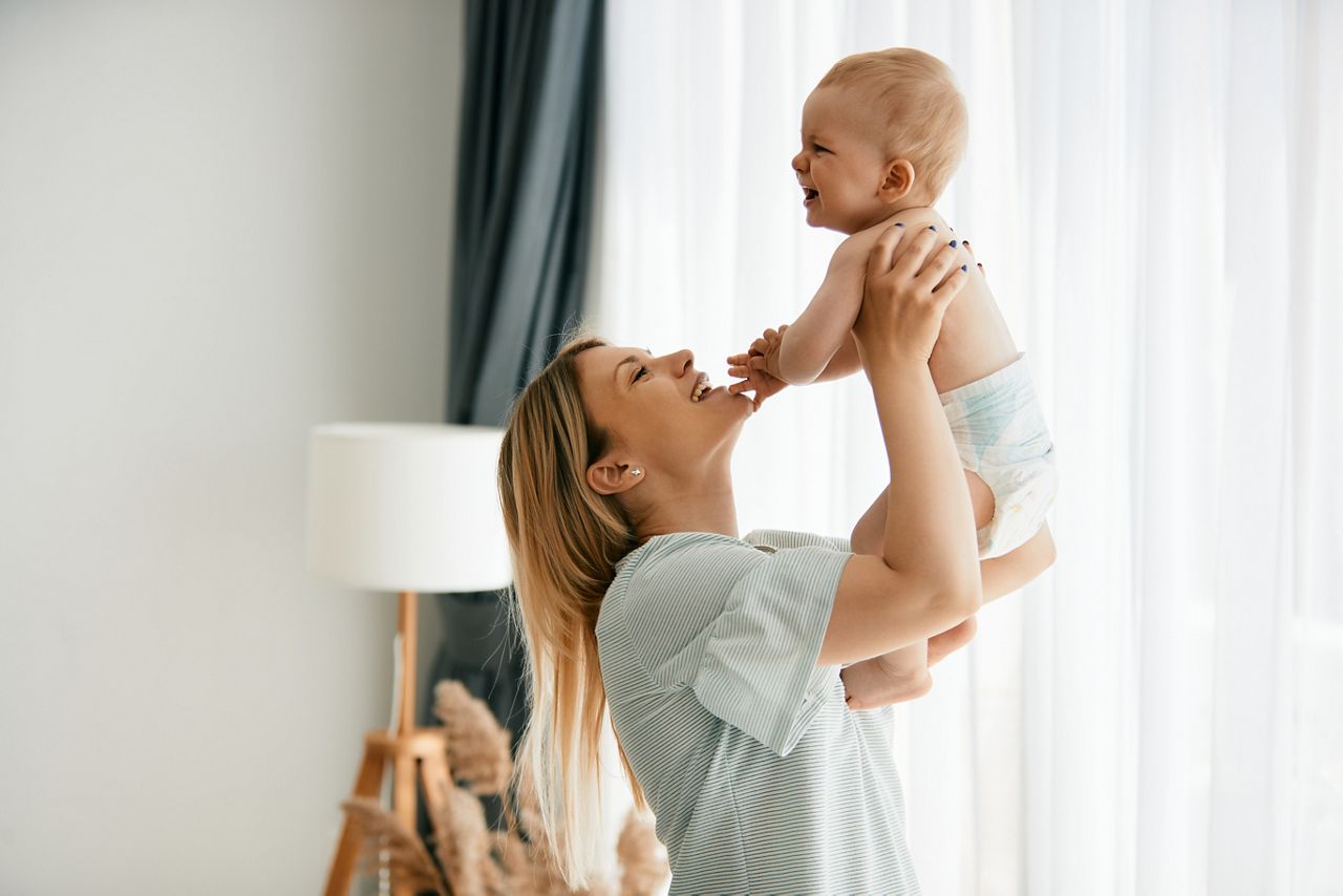 Happy mother trying to cheer up her crying baby boy while playing with his at home.; Shutterstock ID 2067642506; purchase_order: DNC Thumbnails; job: Webinars 1 (50/189); client: ; other: 
