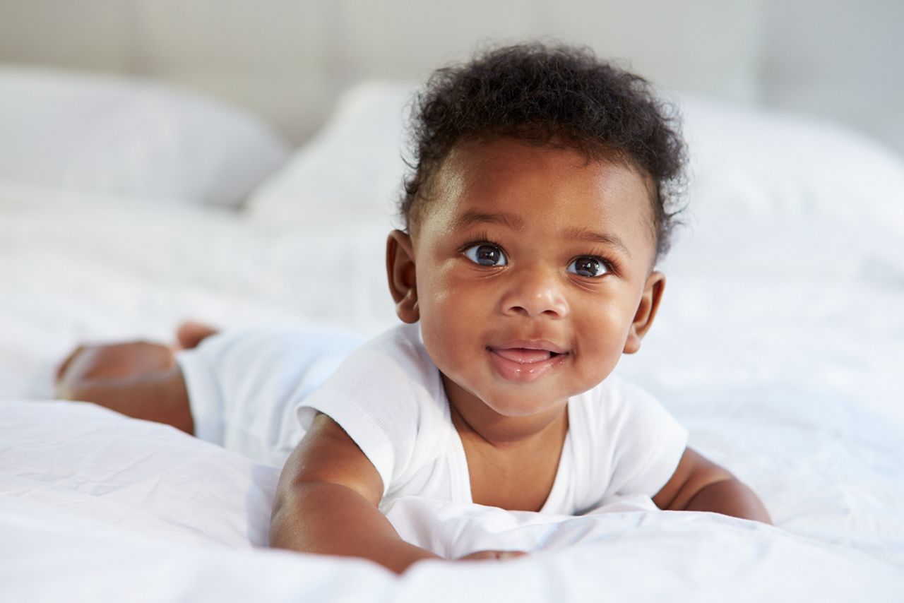 Cute Baby Lying On Tummy In Parent's Bed; Shutterstock ID 207598366; purchase_order: DNC Thumbnails; job: Webinars 1 (50/189); client: ; other: 