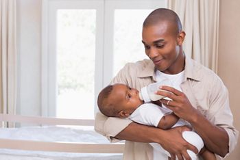 Happy father feeding his baby boy a bottle at home in the bedroom; Shutterstock ID 207783811; purchase_order: DNC Thumbnails; job: Webinars 3 (50/188); client: ; other: 