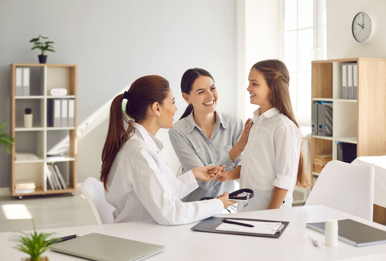 Children's medical care. Happy mother and daughter at medical examination at friendly female pediatrician. Smiling doctor and mother encourage teenage girl during medical consultation at hospital.; Shutterstock ID 2082191524; purchase_order: DNC Thumbnails; job: Collections; client: ; other: 