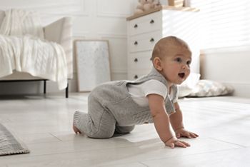 Cute baby crawling on floor at home