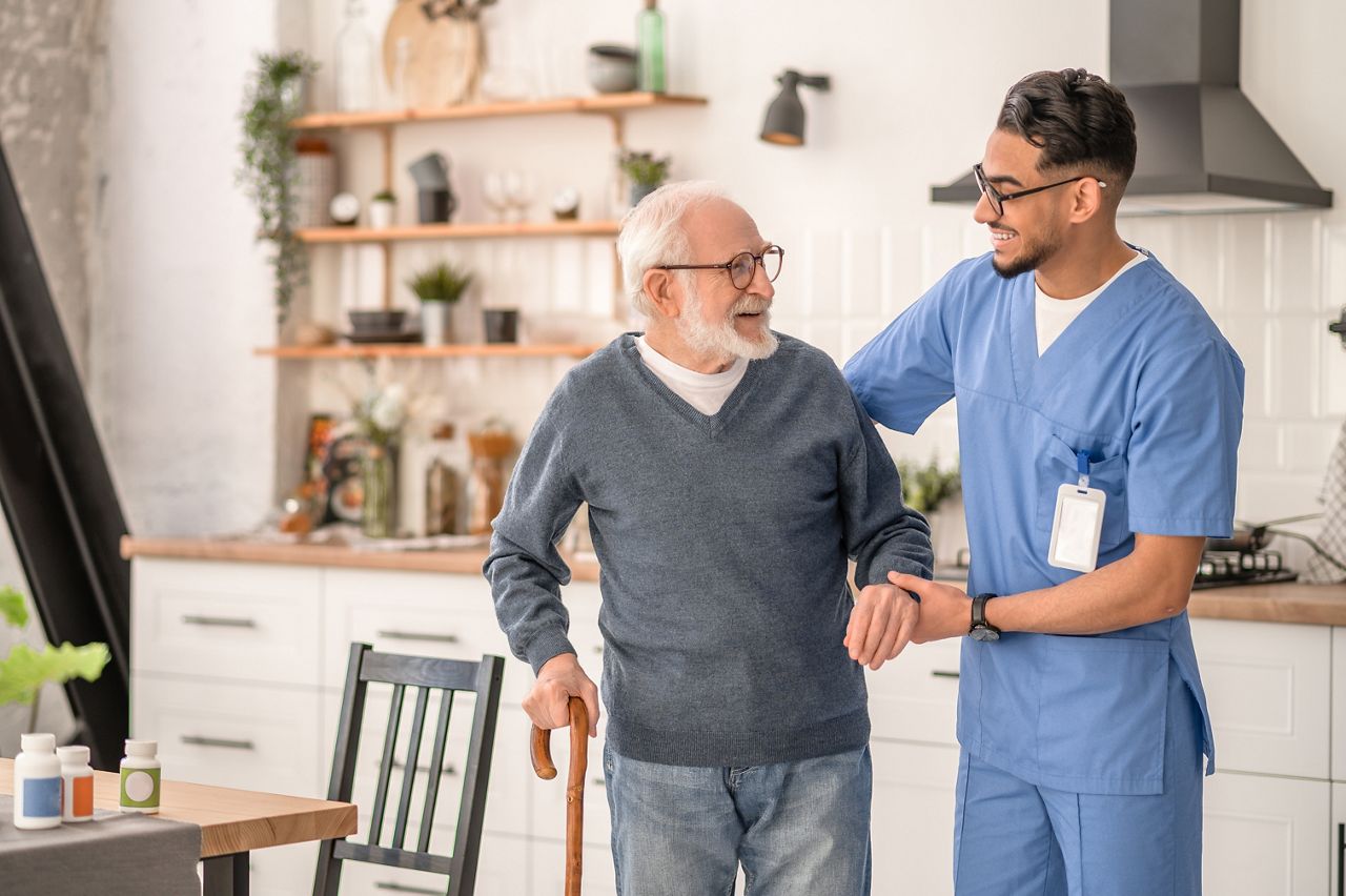 Medical worker helping his patient to move around the apartment; Shutterstock ID 2156665967; purchase_order: DNC Thumbnails; job: Videos; client: ; other: 