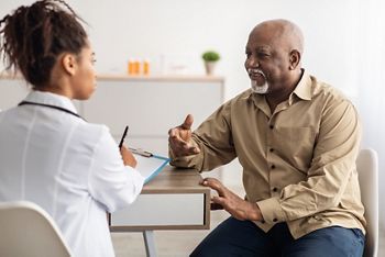 Healthcare, Geriatric Medicine, Medical Check Up. Senior man visiting doctor telling about health complaints, female gp or nurse writing personal information, filling form listening to elderly patient