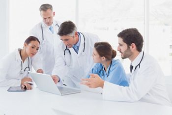 Doctors using a laptop together at work