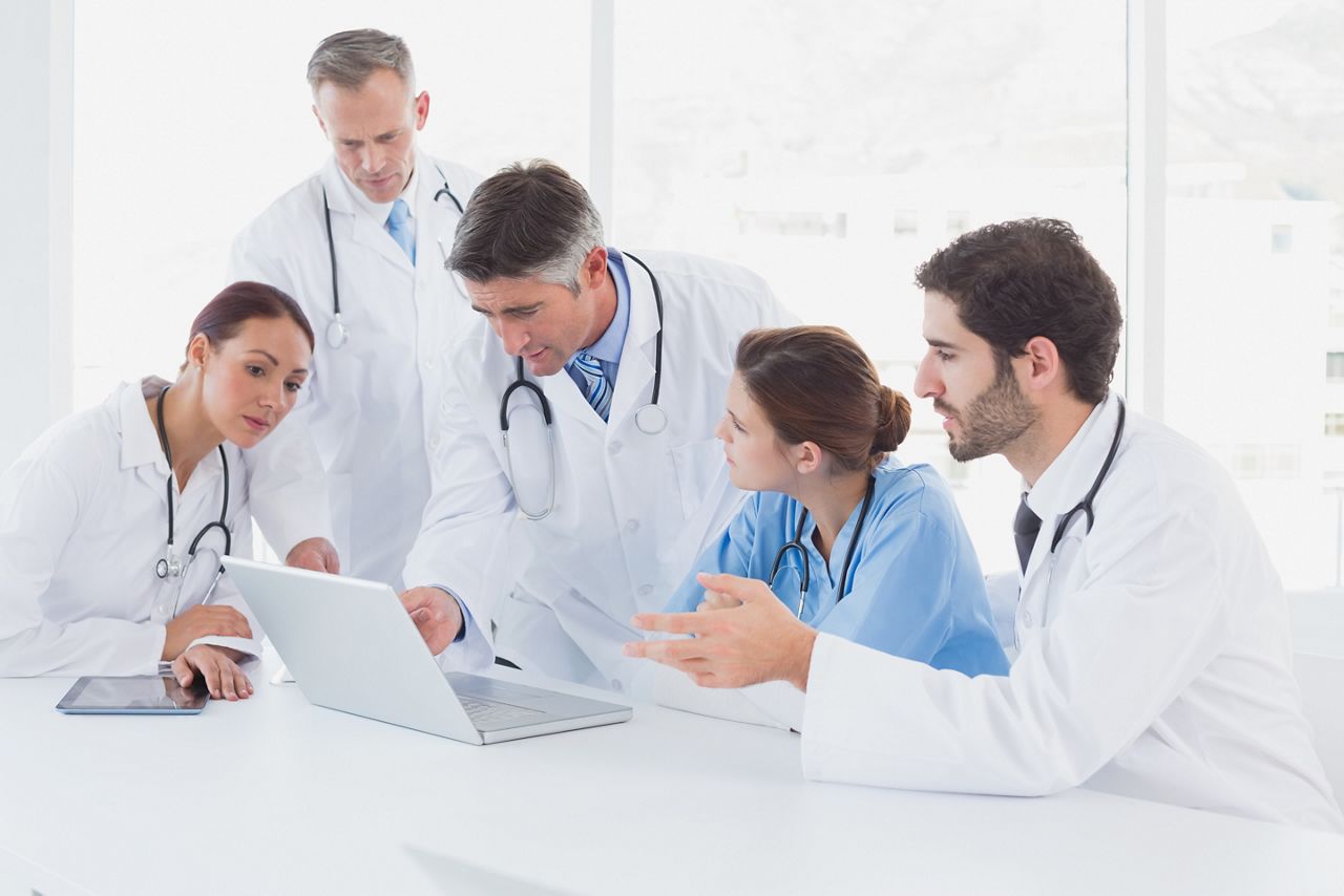 Doctors using a laptop together at work