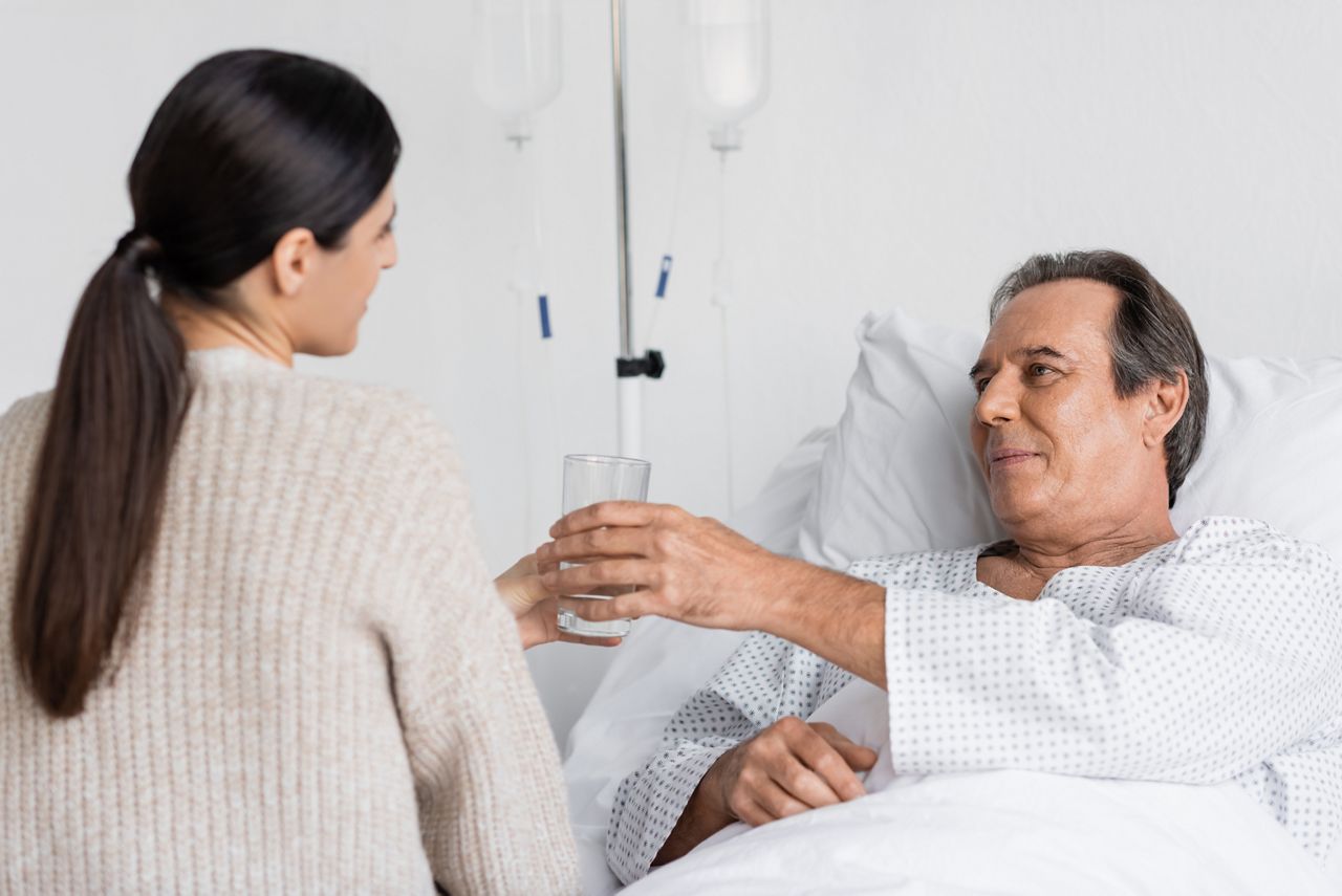 Blurred daughter giving glass of water to senior dad on hospital bed; Shutterstock ID 2247559637; purchase_order: DNC Thumbnails; job: Webinars 2 (50/188); client: ; other: 