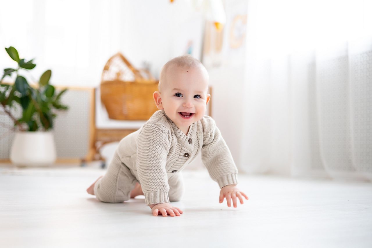 cute little baby boy in a pastel wool knitted suit learning to crawl on the floor in a bright living room, baby smiling, playing, early development of children; Shutterstock ID 2357827881; purchase_order: 25 thumbnail photos ; job: ; client: ; other: 