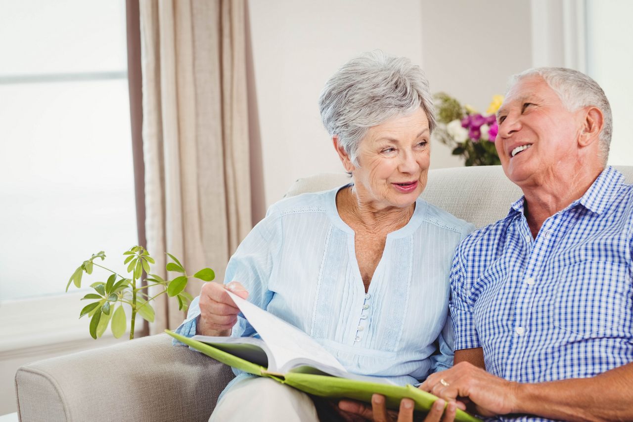 Senior couple sitting on sofa and reading a book in living room; Shutterstock ID 388564108; purchase_order: DNC Thumbnails; job: Articles; client: ; other: 