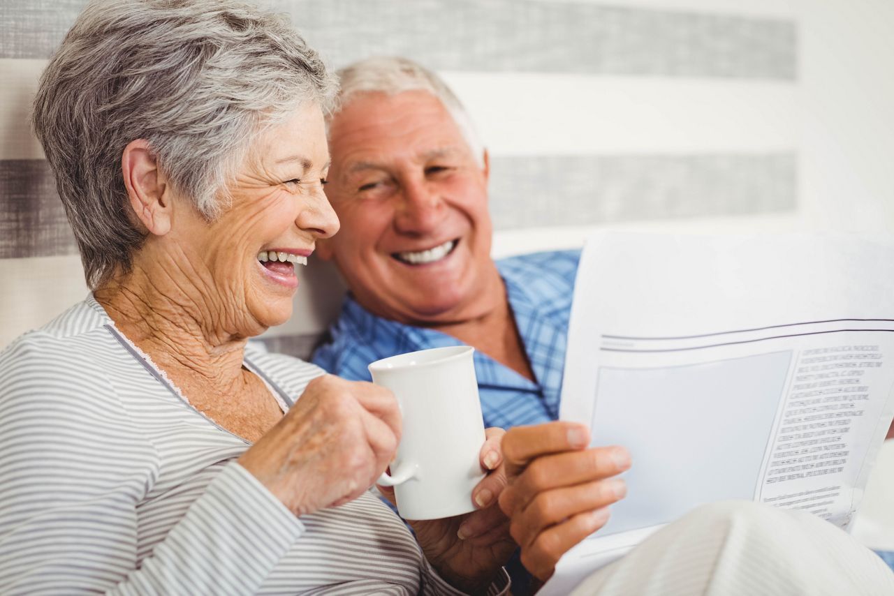 Senior couple laughing while reading newspaper in bedroom; Shutterstock ID 388567021; purchase_order: DNC Thumbnails; job: Videos; client: ; other: 