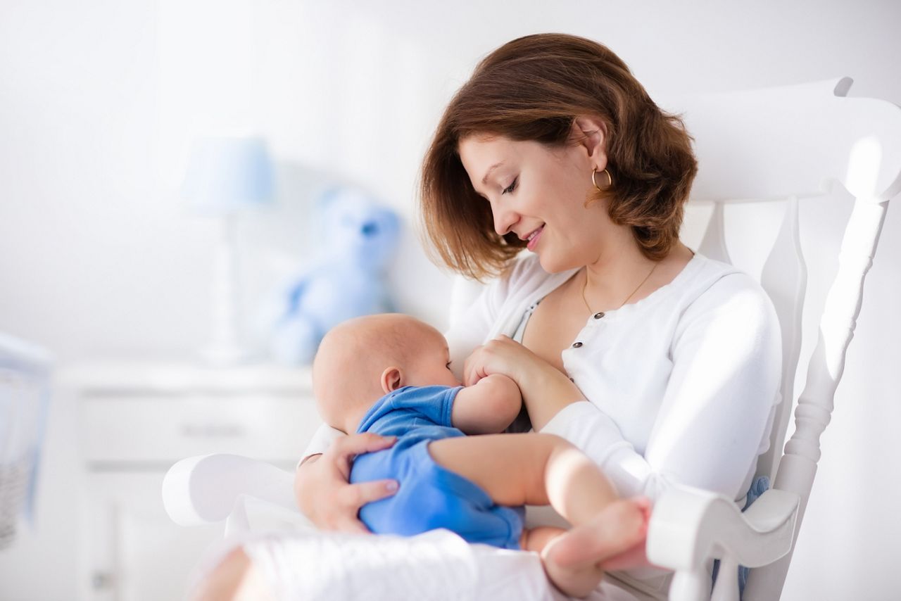 Young mother holding her newborn child. Mom nursing baby. Woman and new born boy in white bedroom with rocking chair and blue crib. Nursery interior. Mother playing with laughing kid. Family at home; Shutterstock ID 388644496; purchase_order: DNC Thumbnails; job: Publications; client: ; other: Replace Fishwife