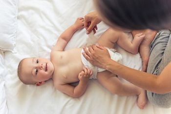 Top view of charming naked little baby looking at his mommy and smiling while she is changing him nappies; Shutterstock ID 464877509; purchase_order: DNC Thumbnails; job: Booklets; client: ; other: 